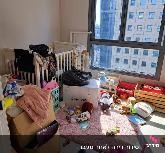 חדר מבולגן עם צעצועים, קופסאות ועריסת תינוק